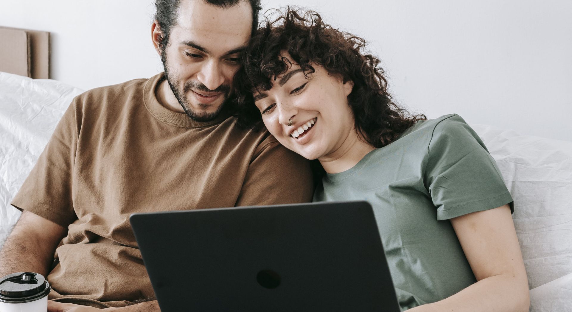 Couple Sitting On A Couch Looking At The Laptop