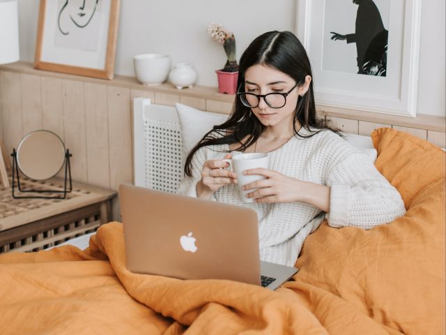 Woman Having  Coffee And Using Laptop In Bed