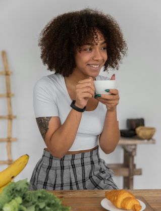 Black woman drinking coffee during breakfast at home